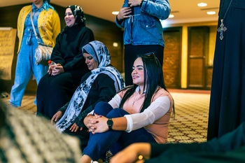 Frauen schauen bei einer multireligiösen Veranstaltung in Ägypten zu. Neben ihnen steht ein Geistlicher mit einer christlichen Kreuzkette. Copyright: GIZ