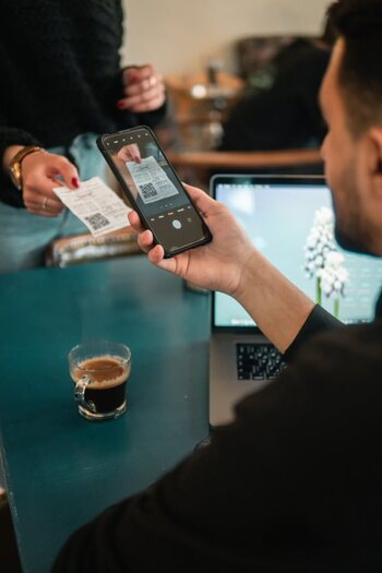 Mann bezahlt mit seinem Handy in einem Café, indem er mit seinem Handy einen QR-Code scannt. 