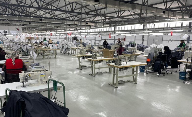 Eine Textilfabrik mit vielen Menschen, die an Nähmaschinen arbeiten.