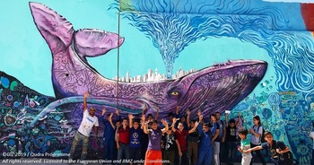 Wandmalerei: SO1 - Außerschulische Aktivitäten - Gruppenbild von Schülern nach dem Bemalen der öffentlichen Prinz-Mohammad-Schule für Jungen in Zarqa, Jordanien - Gemeinsame Kunstprojekte stärken den sozialen Zusammenhalt unter Kindern.