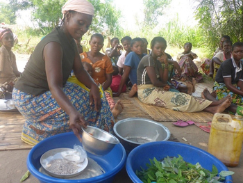 Eine lokale Ausbilderin demonstriert einer Frauengruppe, wie nahrhafte Gerichte aus regionalen Produkten hergestellt werden.