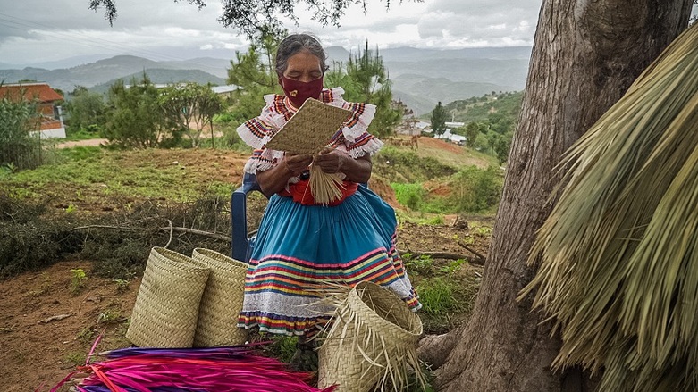 Eine Frau verarbeitet Palmenblätter zu Körben. Copyright: GIZ
