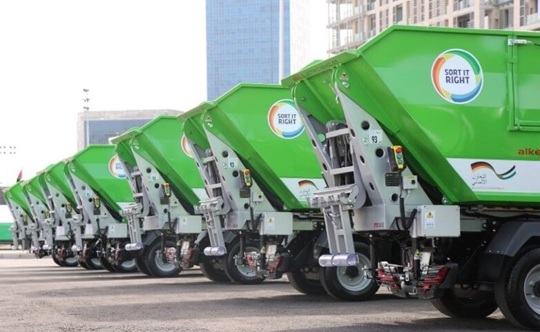 Aufgereihte, grüne Müllfahrzeuge im Hof