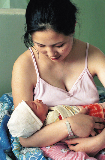Eine Mutter hält ihr Neugeborenes im Arm. 