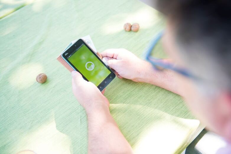 Eine Person hält ein Smartphone in der Hand auf der eine App für Produzent*innen der biologischen Landwirtschaft geöffnet ist.