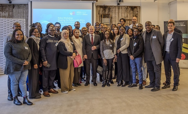 Afrikanische Jungunternehmer*innen posieren auf einem Gruppenfoto mit Bundeskanzler Scholz bei einem Workshop in Berlin 2023.