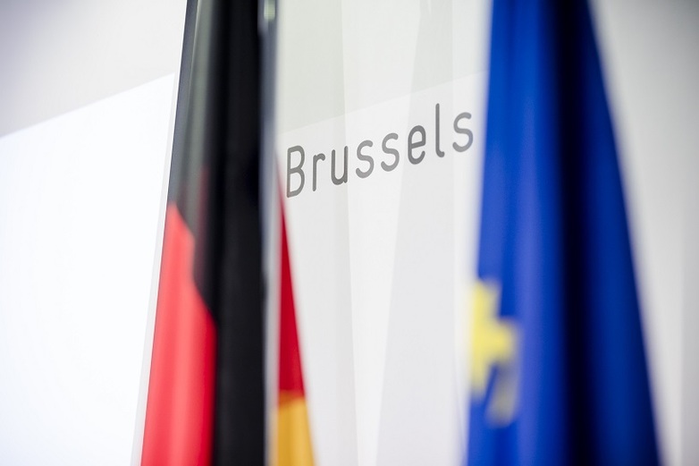 Deutsche und europäische Flagge vor einem Banner mit der Aufschrift „Brussels“. Copyright: GIZ / Repräsentanz Brüssel