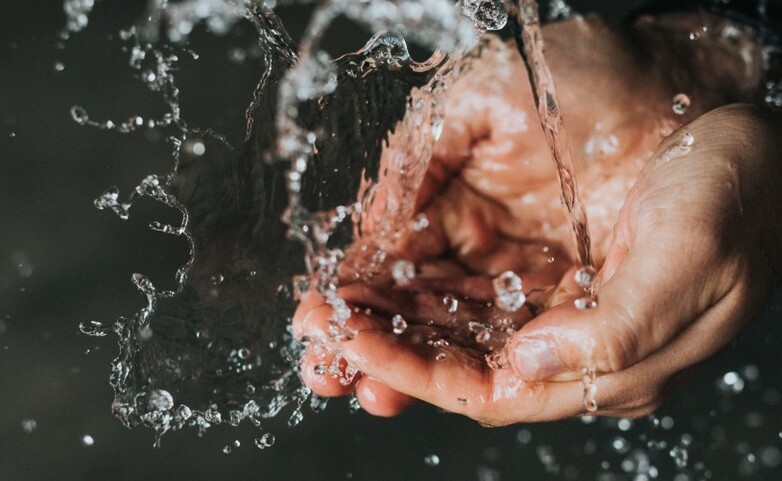 Hände fangen frisches Wasser auf.