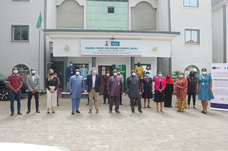 Teilnehmer*innen einer Simulationsübung stehen vor dem Nigerianischen Seuchenkontrollzentrum zusammen. 