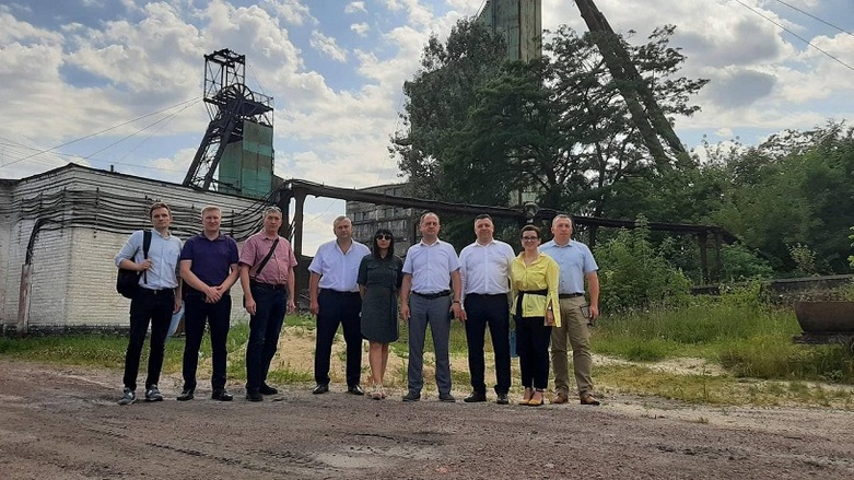 Neun Mitarbeitende in Hemden stehen vor dem Bergwerk in Chervonohrad.