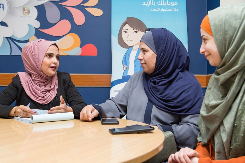 Three women wearing hijabs sit at a round table in a meeting. Copyright: GIZ