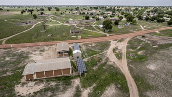 Luftaufnahme einer Solaranlage, die eine Mühle und eine Schälmaschine für Getreide in ländlichen Gebieten mit Strom versorgt.