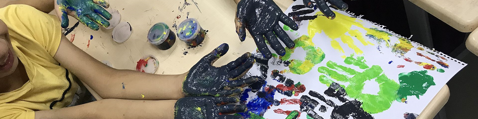 Kinder malen mit Fingerfarben.