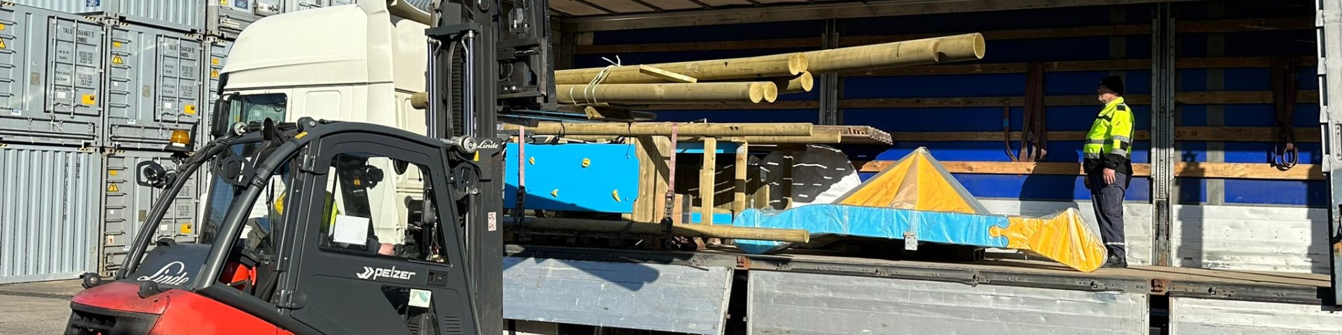 Ein Gabelstapler transportiert Spielplatzgeräte zu einem Lastwagen.