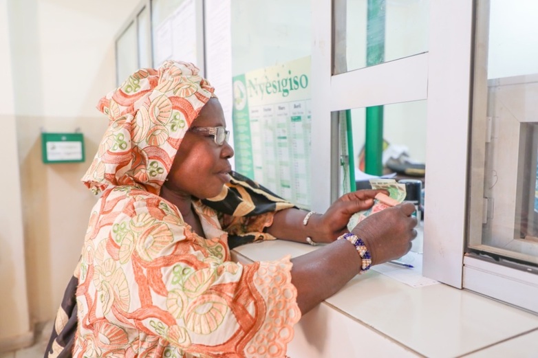Eine Frau steht an einem Schalter einer Finanzinstitution und hält Geldscheine in der Hand. © GZ/Oumar COULIBALY, 2020