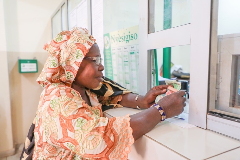 Eine Frau steht an einem Schalter einer Finanzinstitution und hält Geldscheine in der Hand. © GZ/Oumar COULIBALY, 2020