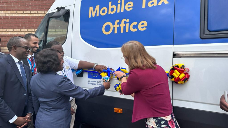 Mehrere Personen weihen ein Auto mit der Aufschrift „Mobile Tax Office“ ein.