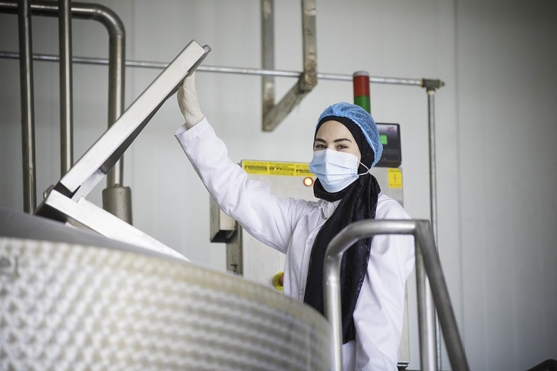 Eine Frau in Laborkittel und Schutzkleidung arbeitet im Rahmen des PALM-Praktikant*innenprogramms in einer Fabrik. Copyright: GIZ / Ameen Saeb.