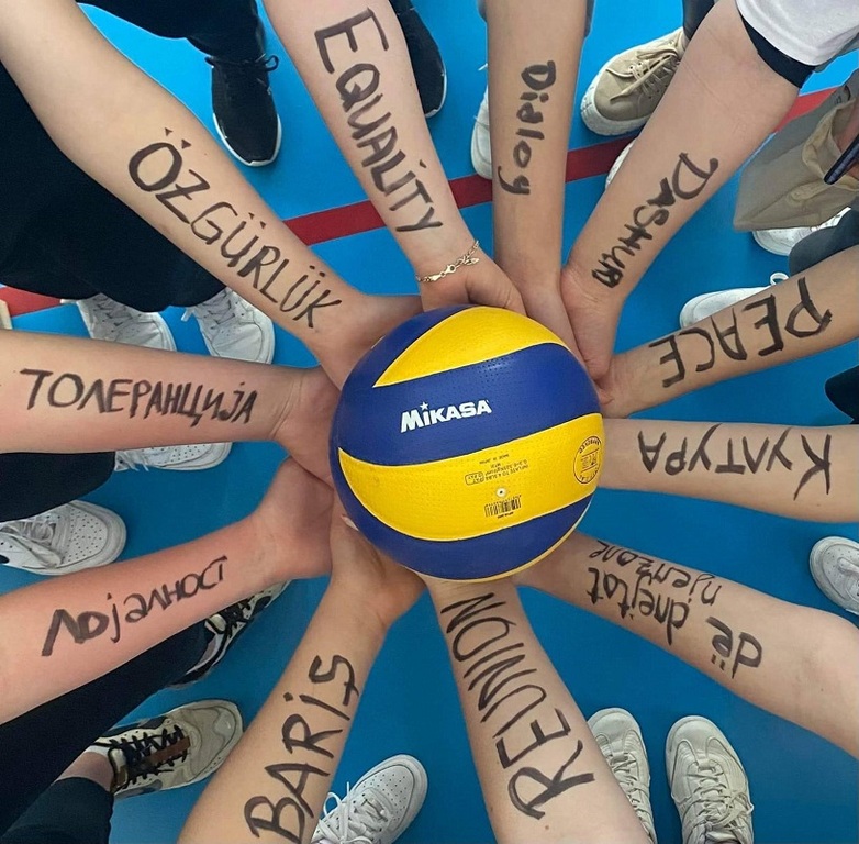 Jugendliche halten gemeinsam einen Volleyball. Auf jedem Unterarm ist ein europäischer Wert notiert. Copyright: GIZ.