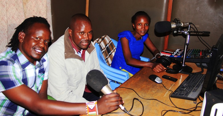 Drei Radiojournalist*innen sitzen in einer Radiostation.
