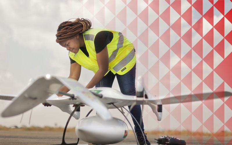 Eine Frau in einer Warnweste arbeitet an einer Drohne.