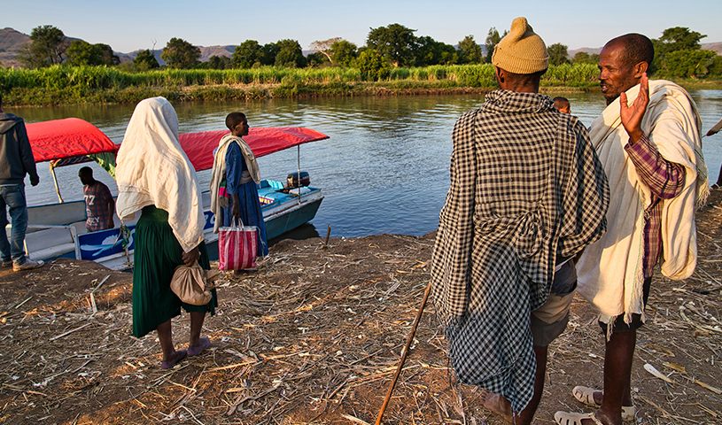 Eine Gruppe Menschen steht am Ufer eines Flusses.