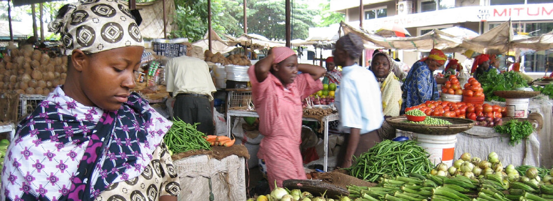 Frau inmitten bunter Feldfrüchte auf einem Markt in Malaysia 