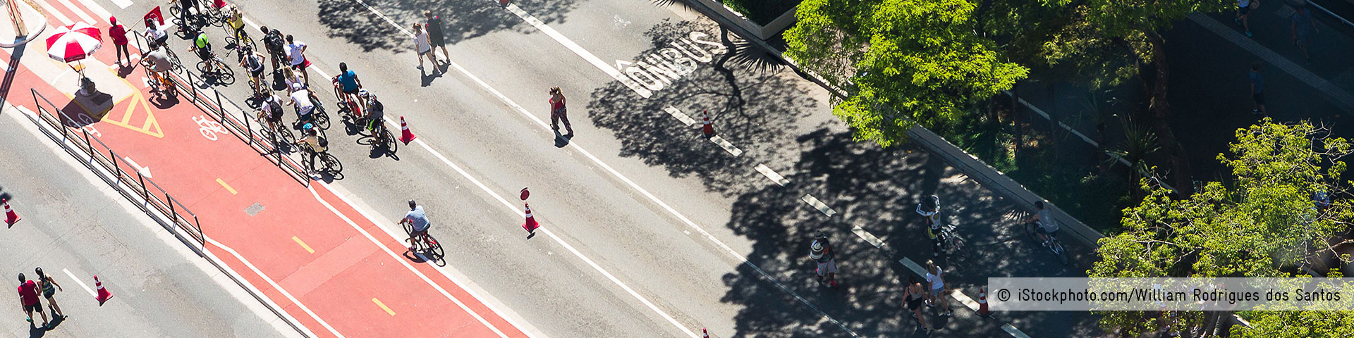 View from above of a road with cycle path marked in red with many people cycling on it. © iStockphoto.com/William Rodrigues dos Santos