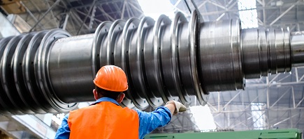 A person wearing a hard hat is working on a large metal device.
