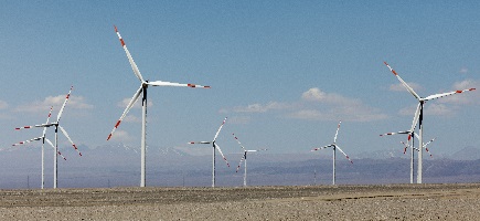 Windturbines with mountains in the background.