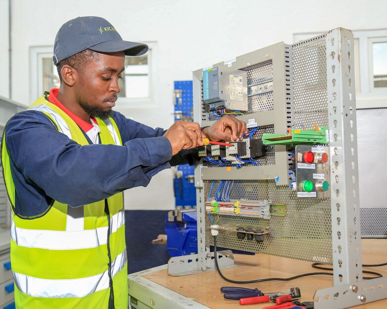 A young man adjusts a series of electrical components. © GIZ