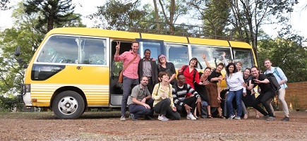 A group of people in front of a yellow bus.