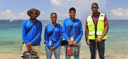 Four people in working gear on a beach.