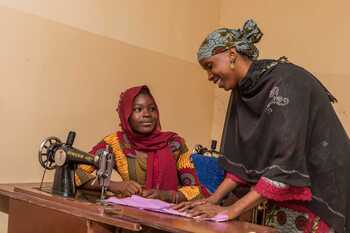 A seamstress and a trainee at a sewing machine.