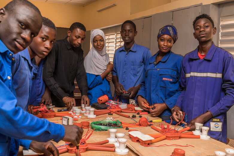 Young electricians standing around a table with cables and tools.