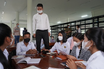 A person standing in front of a group of people wearing face masks.