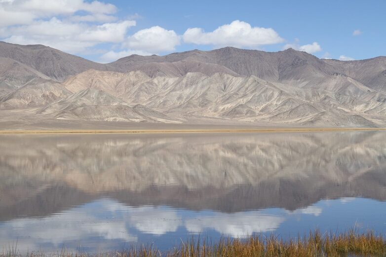 A bleak mountain range is reflected in a lake.