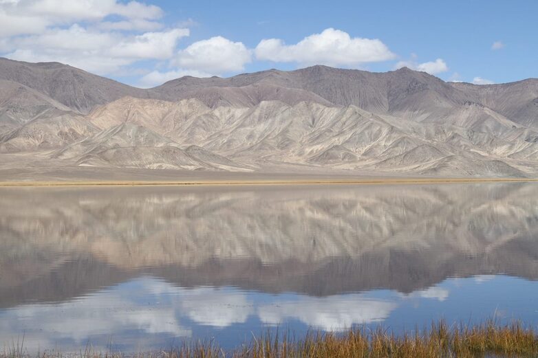 A bleak mountain range is reflected in a lake.