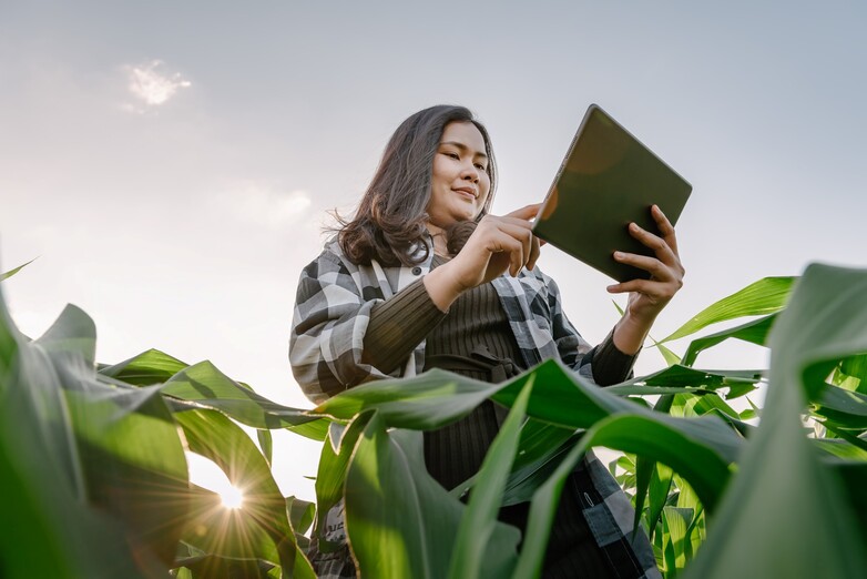 A woman standing in a field holding a tablet.
