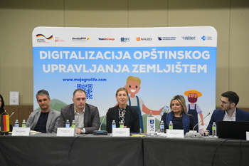 A group of people sit in front of an illustration of the digitalization of the economy in the European Union.