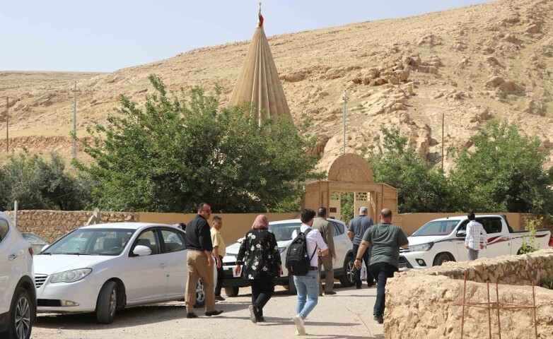 People walking on a road where there is a Yazidi shrine