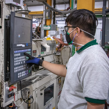 An automation trainee standing in a workshop and preparing the programming. 