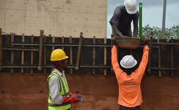 Construction workers with hard hats and high-visibility waistcoats at work on a building site.