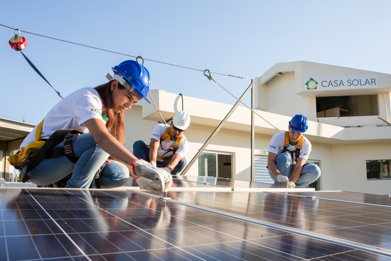 Three technicians installing photovoltaic modules on a SENAI training centre.