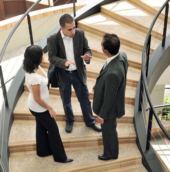 Drei Personen stehen auf einer Wendeltreppe und sprechen miteinander