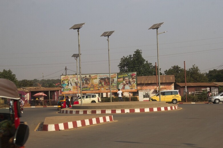 Vehicles drive around a roundabout that has been upgraded using tax revenues from mining. Solar-powered street lights are installed on the roundabout. Copyright: GIZ