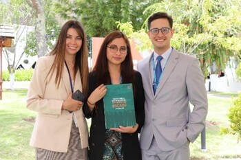 Three people stand together. A woman holds a document.