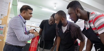 A man explains a fire extinguisher to three people.