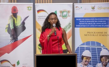 A young woman at a lectern speaks at an event about a mentoring programme for students. © GIZ
