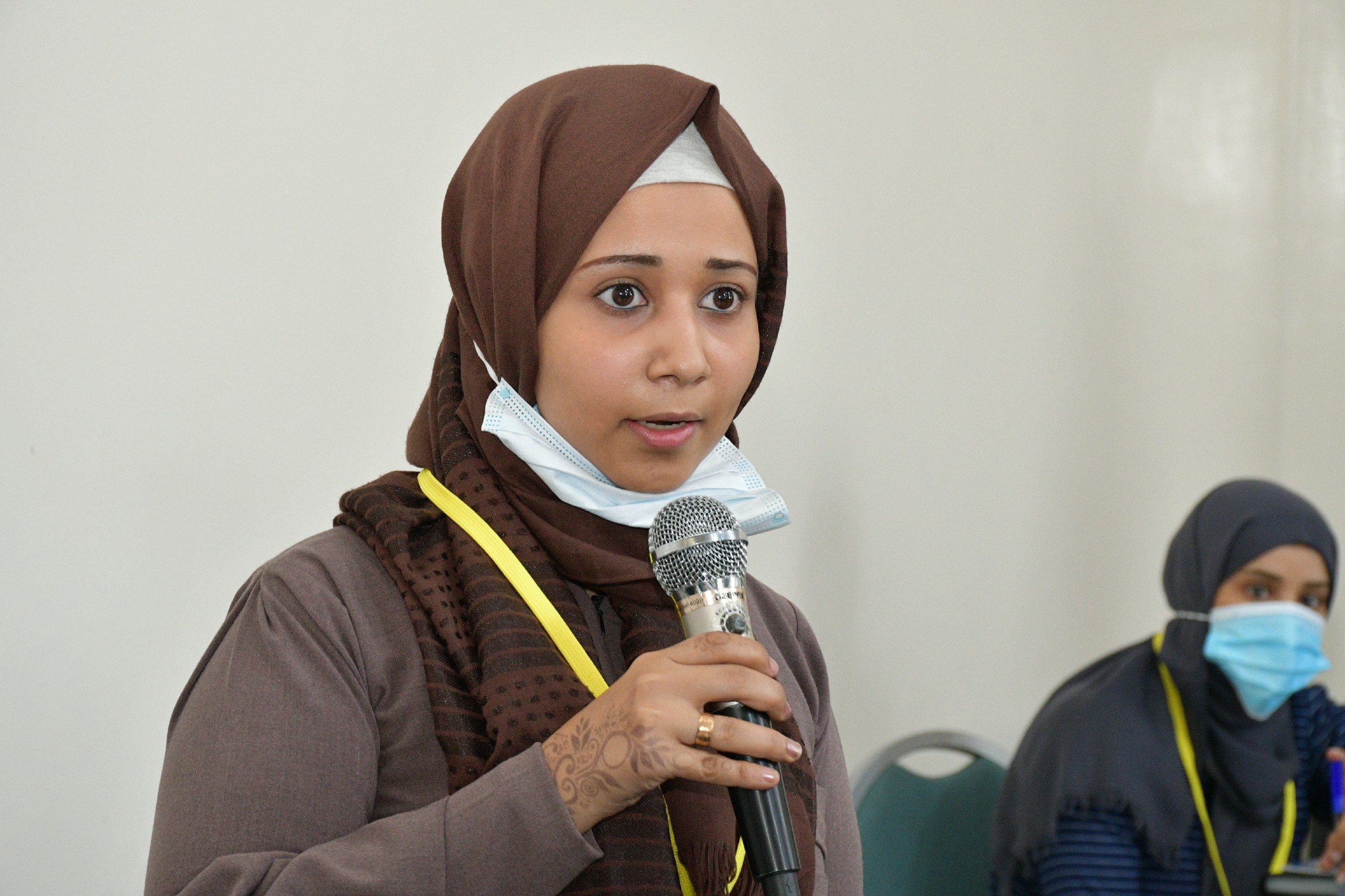 A woman with a microphone speaking at a networking event for women and women’s initiatives in Taiz. (Photo: GIZ).